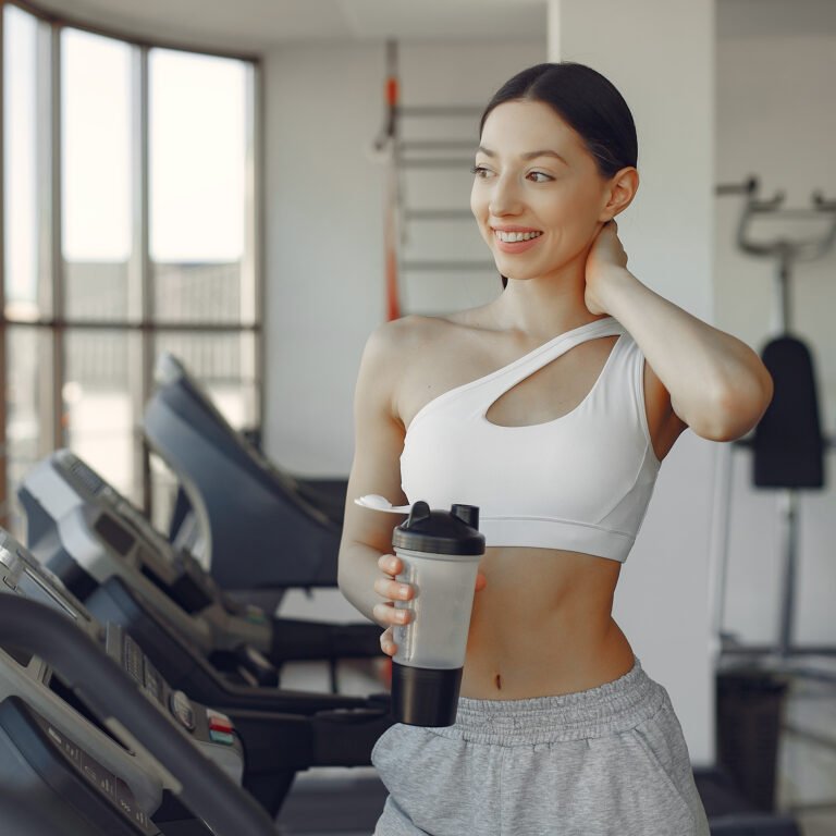Beautiful girl in a gym. A woman on a racetrack. Lady in a white top.